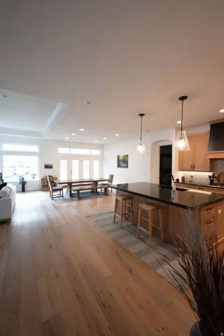 Open-concept living space with wide plank wood-finish flooring, recessed lighting, and a tray ceiling
