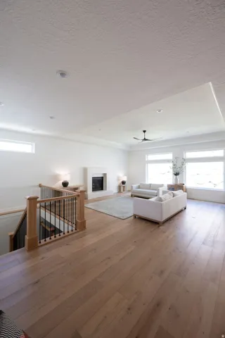 Open-concept living space featuring wood-finish flooring, a contemporary fireplace with a light-colored mantel, and large windows