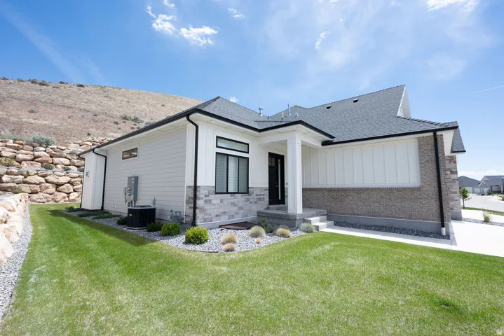 Modern exterior featuring white vertical and horizontal siding, stone veneer accents, dark trim, and a dark asphalt shingle roof
