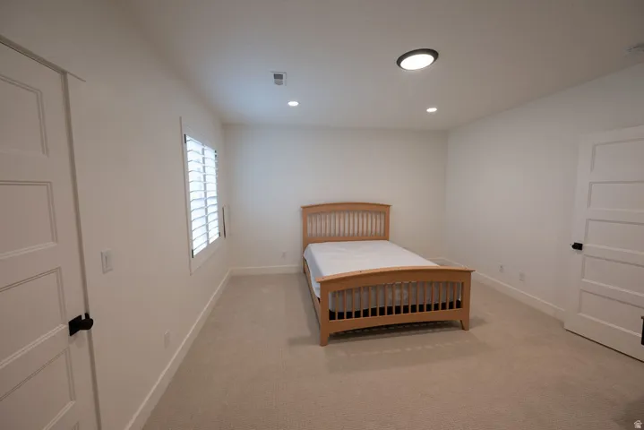 Room featuring neutral-toned carpet flooring, white walls, and a window with white plantation shutters