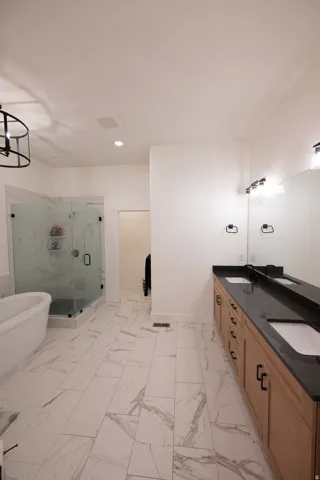 Spacious bathroom featuring large format tile flooring, a freestanding soaking tub, and a glass-enclosed shower