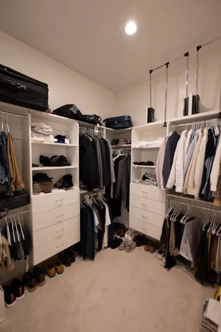 Custom-built closet system featuring multiple hanging rods, integrated shelving, and drawer storage