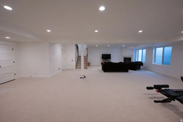 Spacious lower level featuring plush carpeting, recessed lighting, white trim, a stone fireplace, and three egress windows
