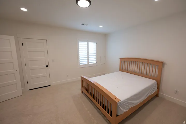Bright room with neutral carpeting, recessed lighting, white window shutters, and white five-panel interior doors