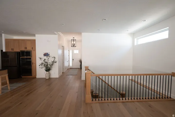 Hardwood-finish flooring throughout, featuring a natural wood newel post and baluster system with black metal spindles