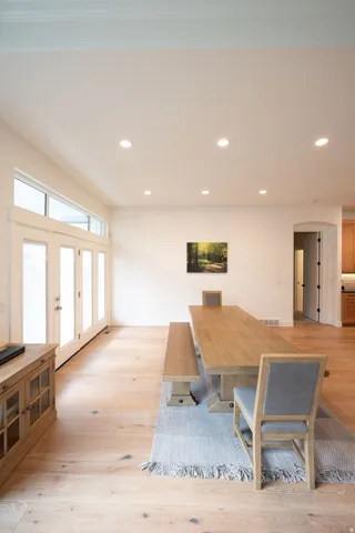 Spacious room featuring light wood-finish flooring, recessed lighting, and a white color palette