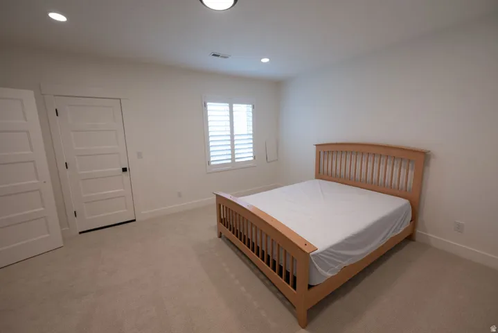 Carpeted room featuring white walls, a single window with white plantation shutters, and two five-panel interior doors with black hardware