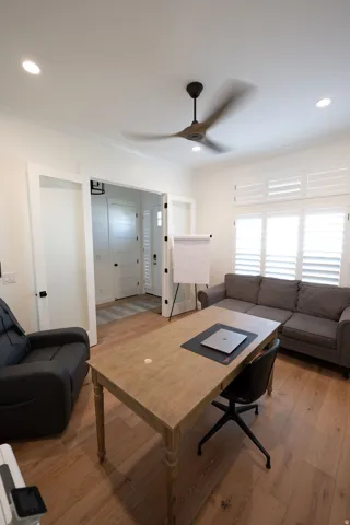 Light-filled interior space featuring wood-finish flooring, white plantation shutters, recessed lighting, and a contemporary ceiling fan