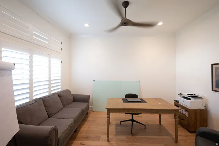Spacious room featuring wood-finish flooring, white walls, and crown molding