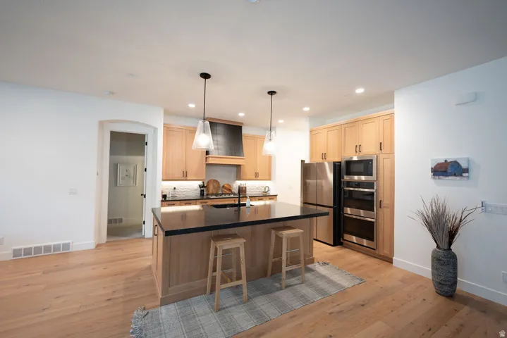 Modern kitchen featuring blonde wood-finish flooring and white walls