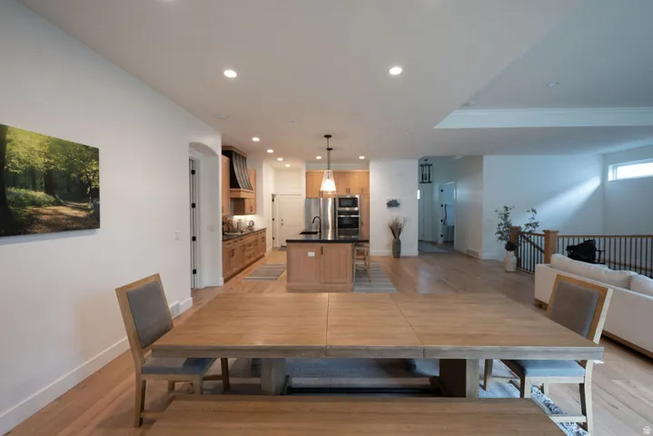 Open-concept living space featuring wood-finish flooring, recessed lighting, and a kitchen with stainless steel appliances, dark countertops, and wood cabinetry