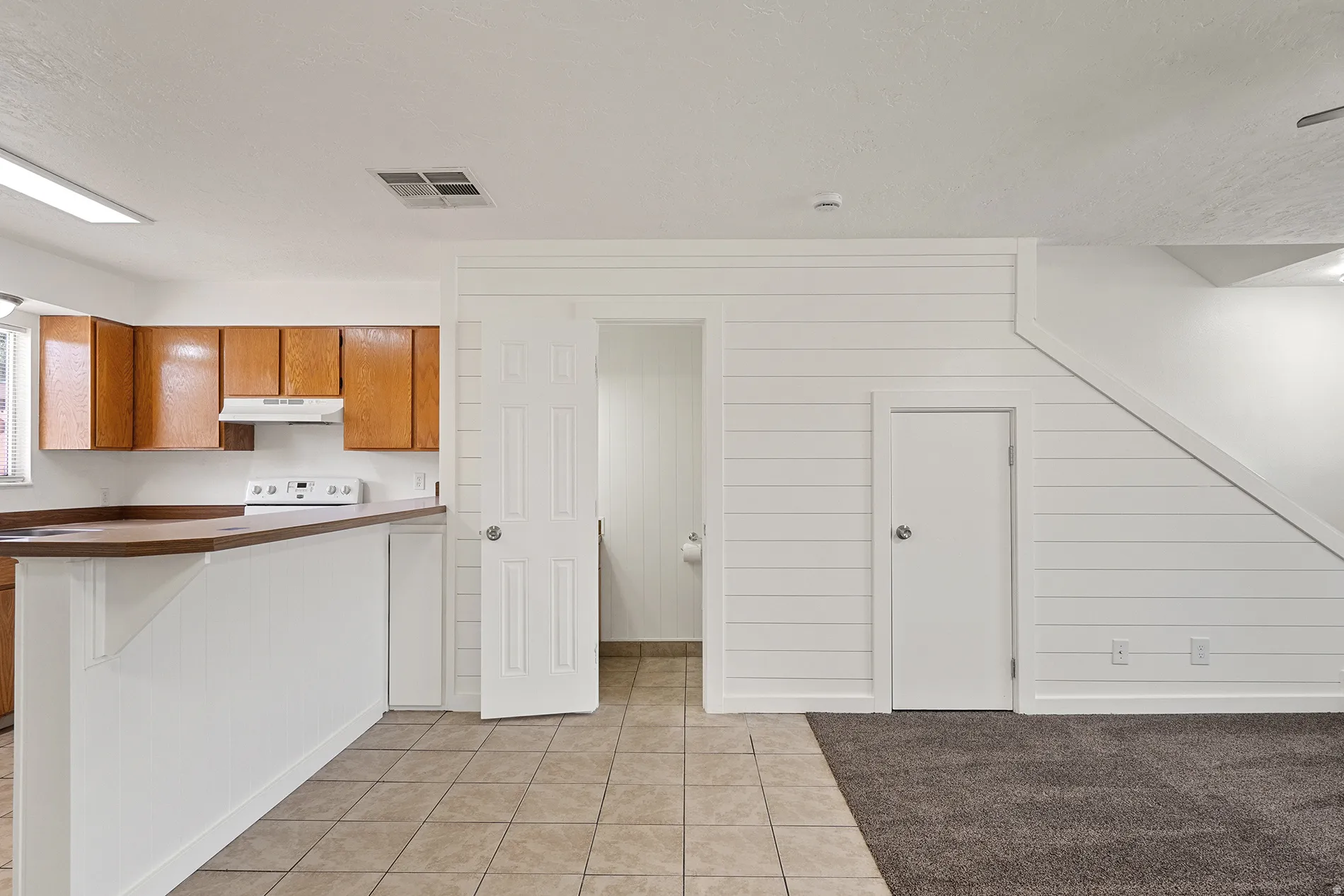 Kitchen featuring wood cabinetry, white appliances, and a breakfast bar with a wood-finish countertop