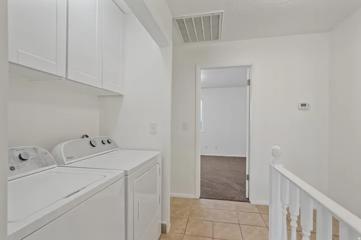 Laundry area featuring white cabinetry and tile flooring