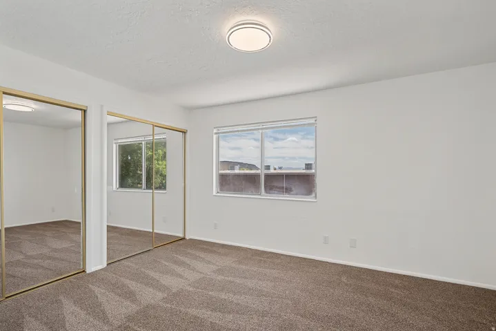Bedroom featuring light brown patterned carpeting, white walls, and a modern ceiling light fixture