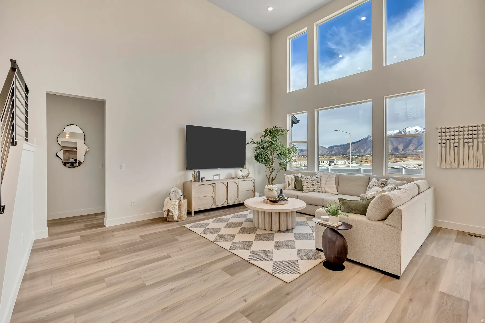 Two-story living area featuring wood-finish flooring, a contemporary staircase with metal balusters, and a high ceiling