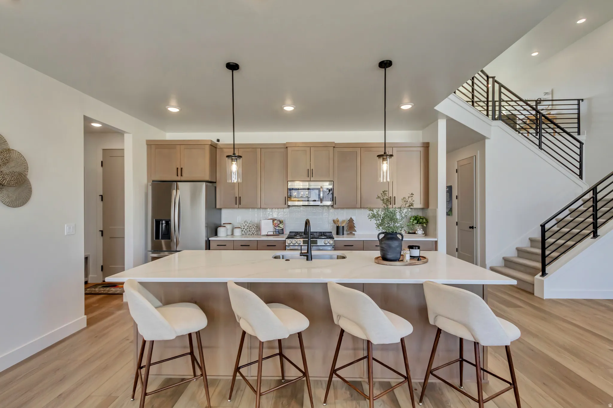 Bright kitchen featuring an expansive island with a light-toned countertop and pendant lighting