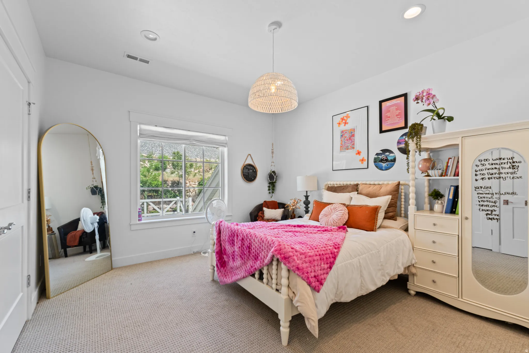 Bright room featuring white walls, textured carpeting, a large window with white trim, and a woven pendant light fixture