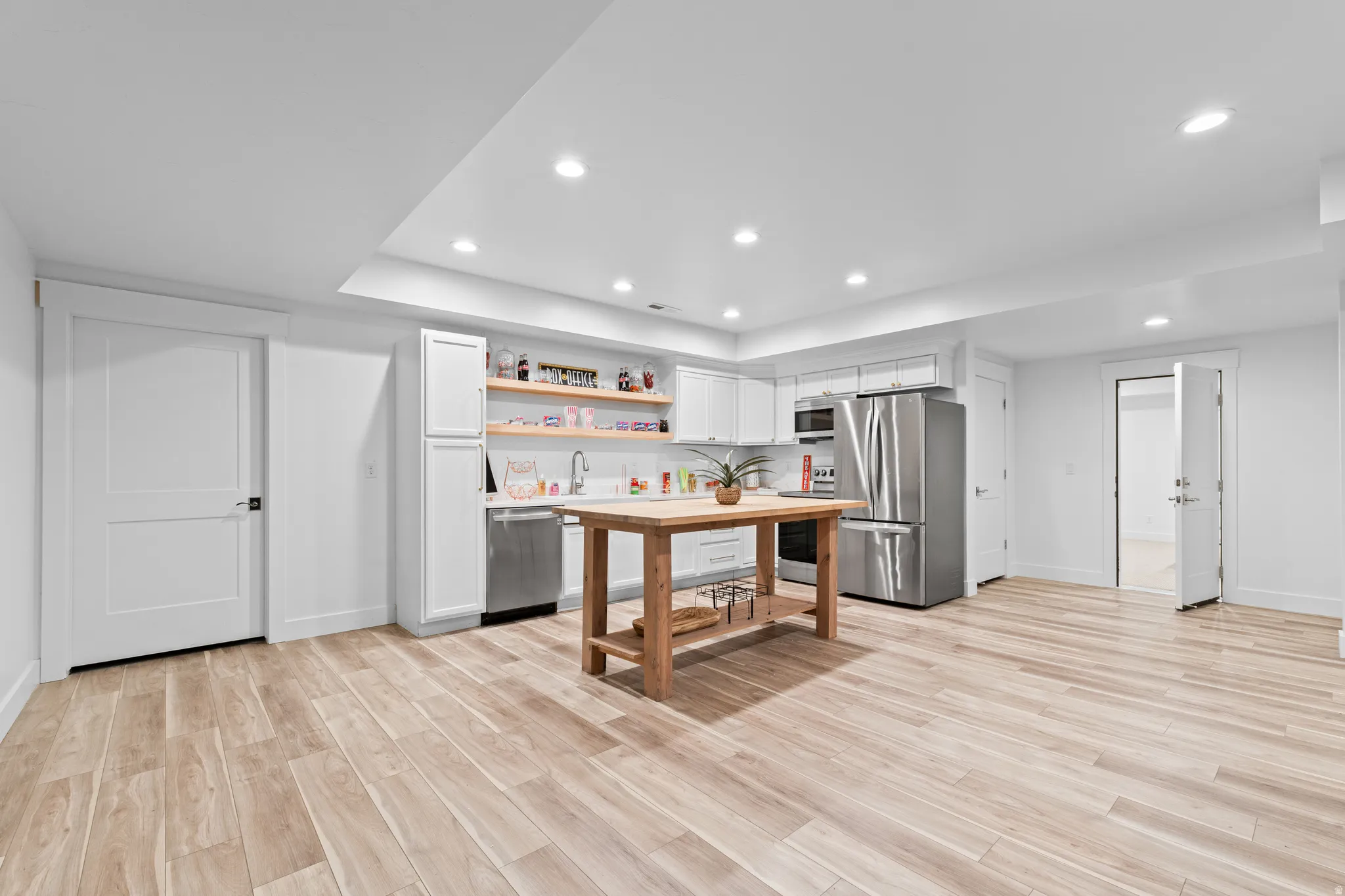 Open-concept space featuring wood-finish flooring, recessed lighting, and a modern kitchen with white cabinetry