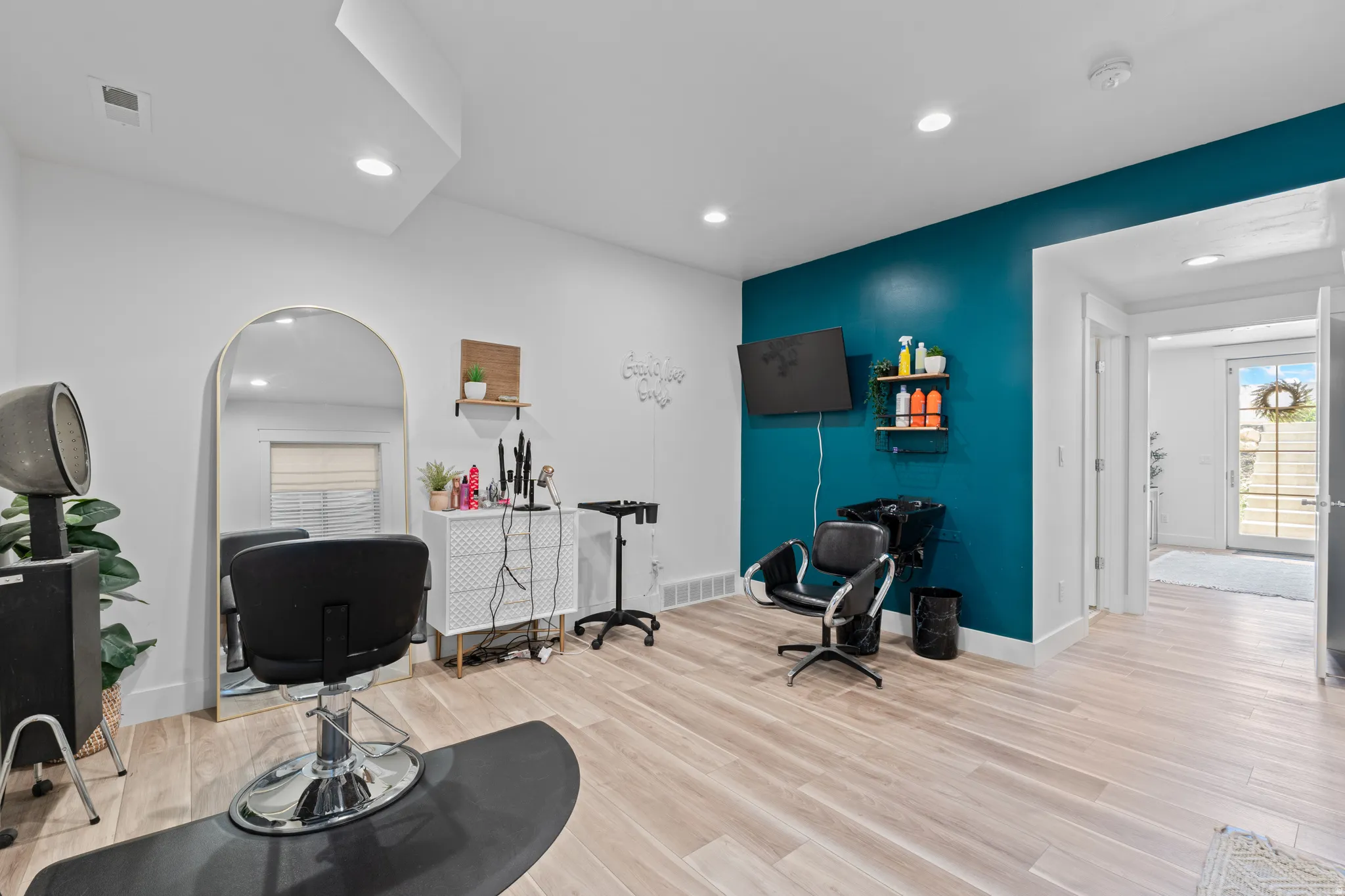 Spacious room featuring wood-finish flooring, a vibrant accent wall, recessed lighting, and a full-light glass door leading to the exterior