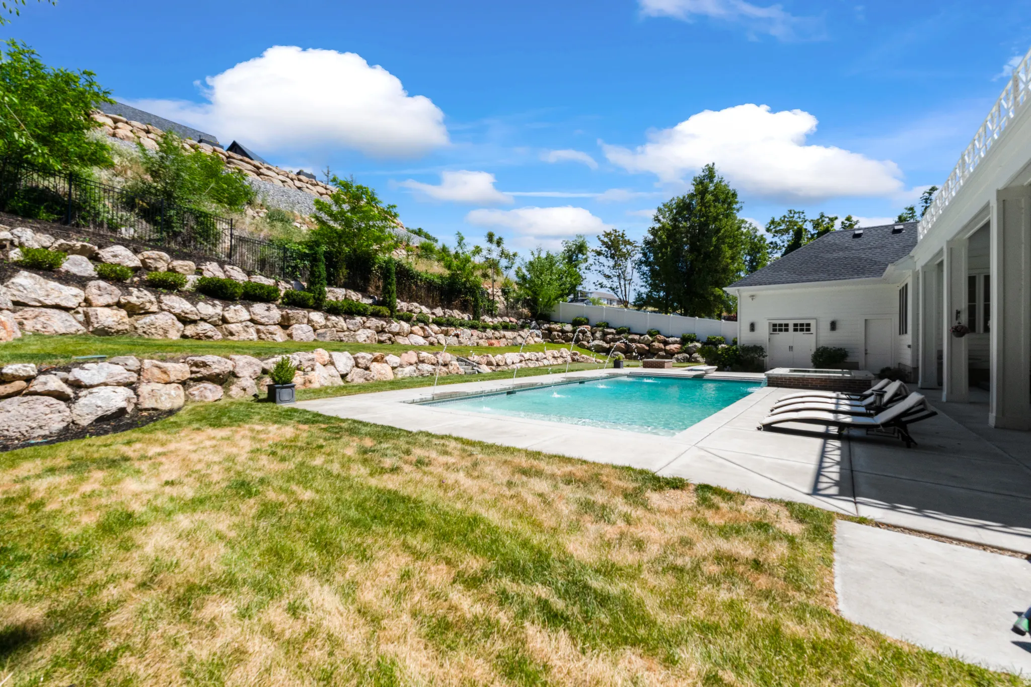 Outdoor swimming pool with integrated spa and concrete surround
