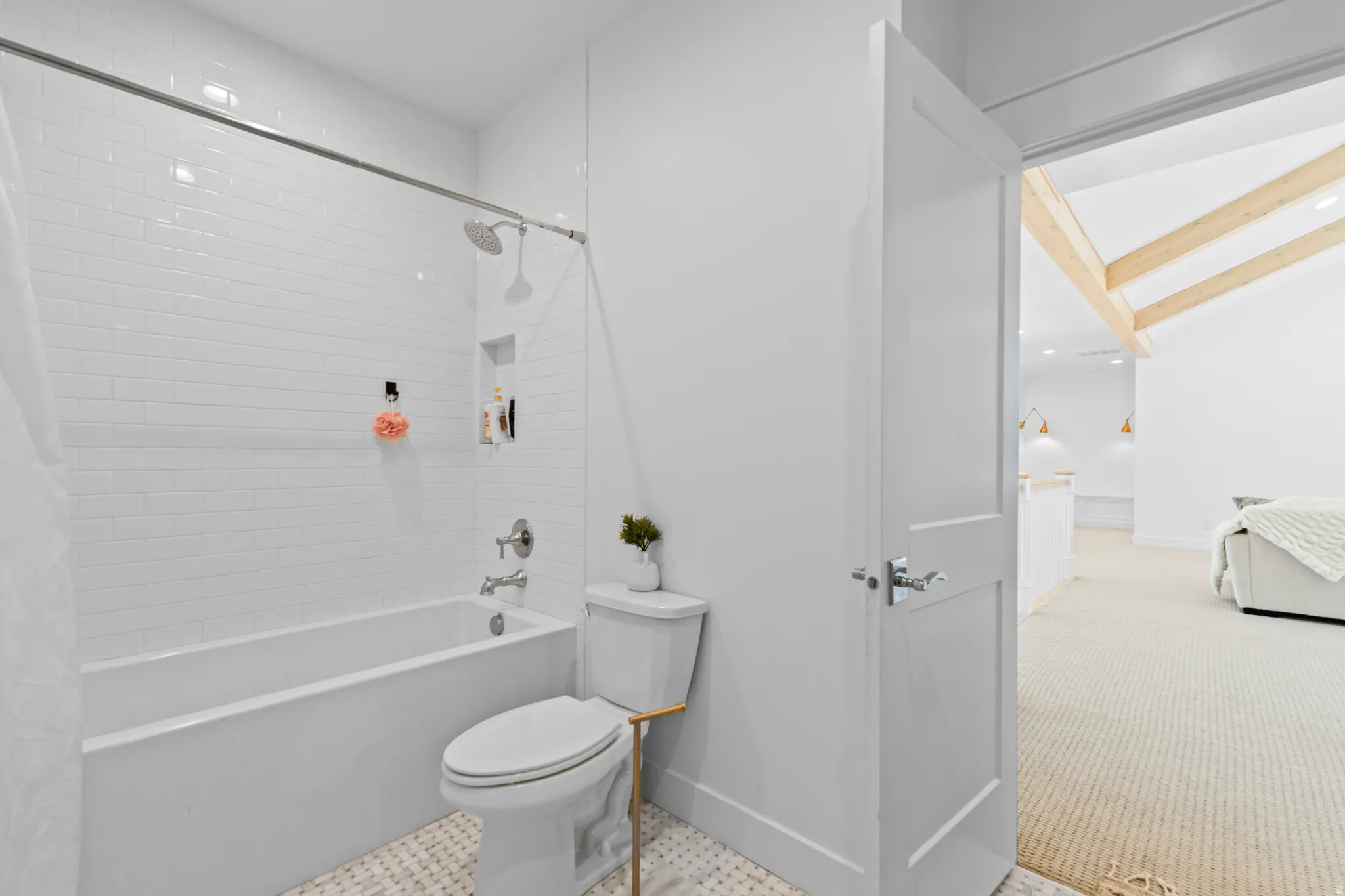 Bathroom featuring a subway-tiled tub/shower combination with a built-in niche, a white toilet, and patterned floor tiles