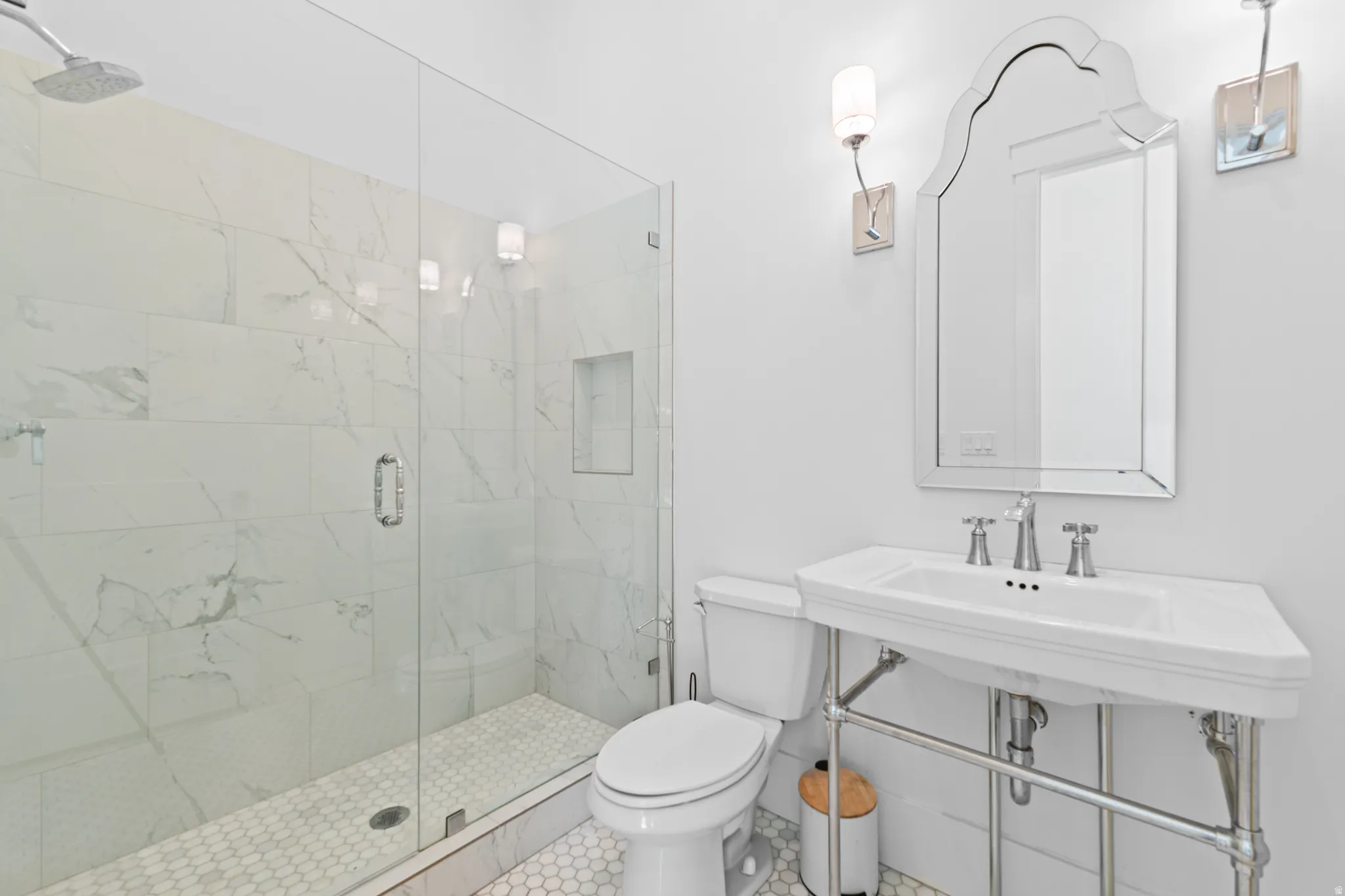 Bathroom featuring a glass-enclosed shower with white marble-look tile, a built-in shower niche, and a rain showerhead