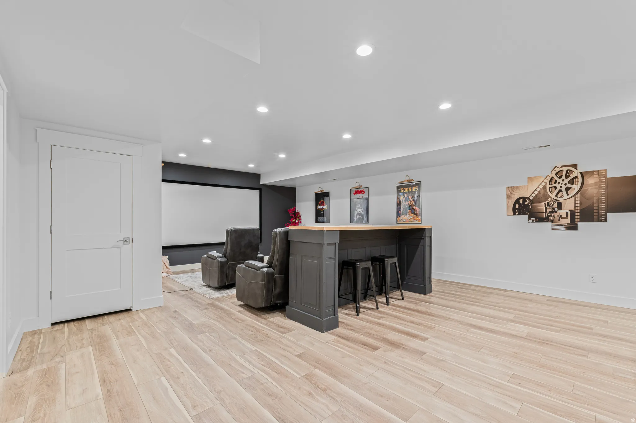Spacious entertainment area featuring wood-finish flooring, recessed lighting, and a built-in bar with a wooden countertop