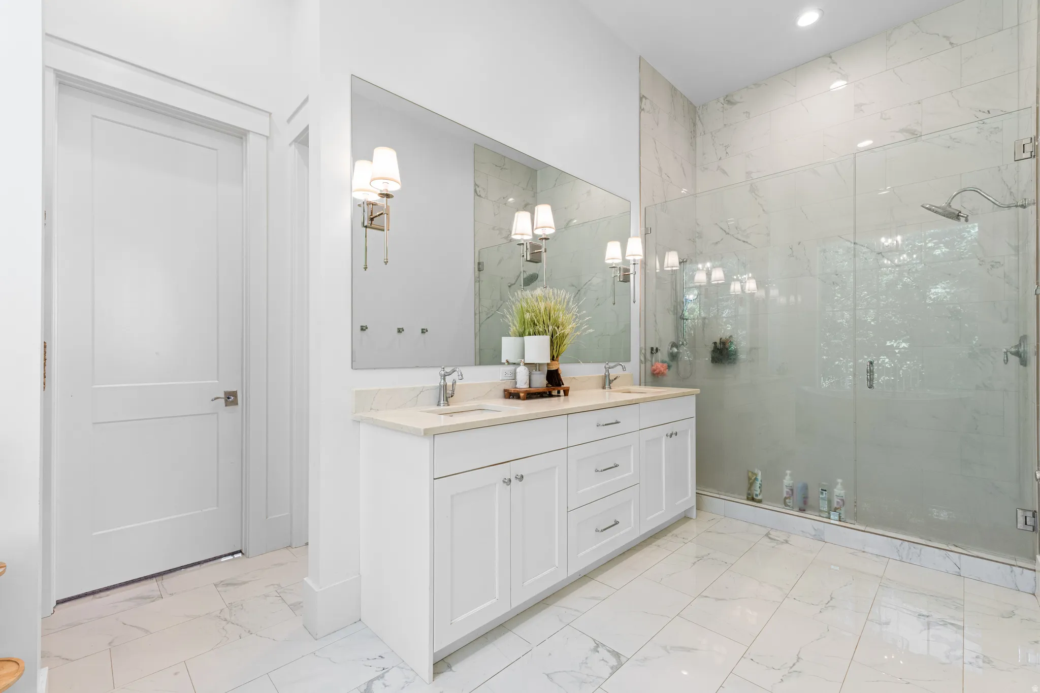 White marble-look tile flooring with a dual vanity featuring light-colored countertops, undermount sinks, and brushed nickel fixtures