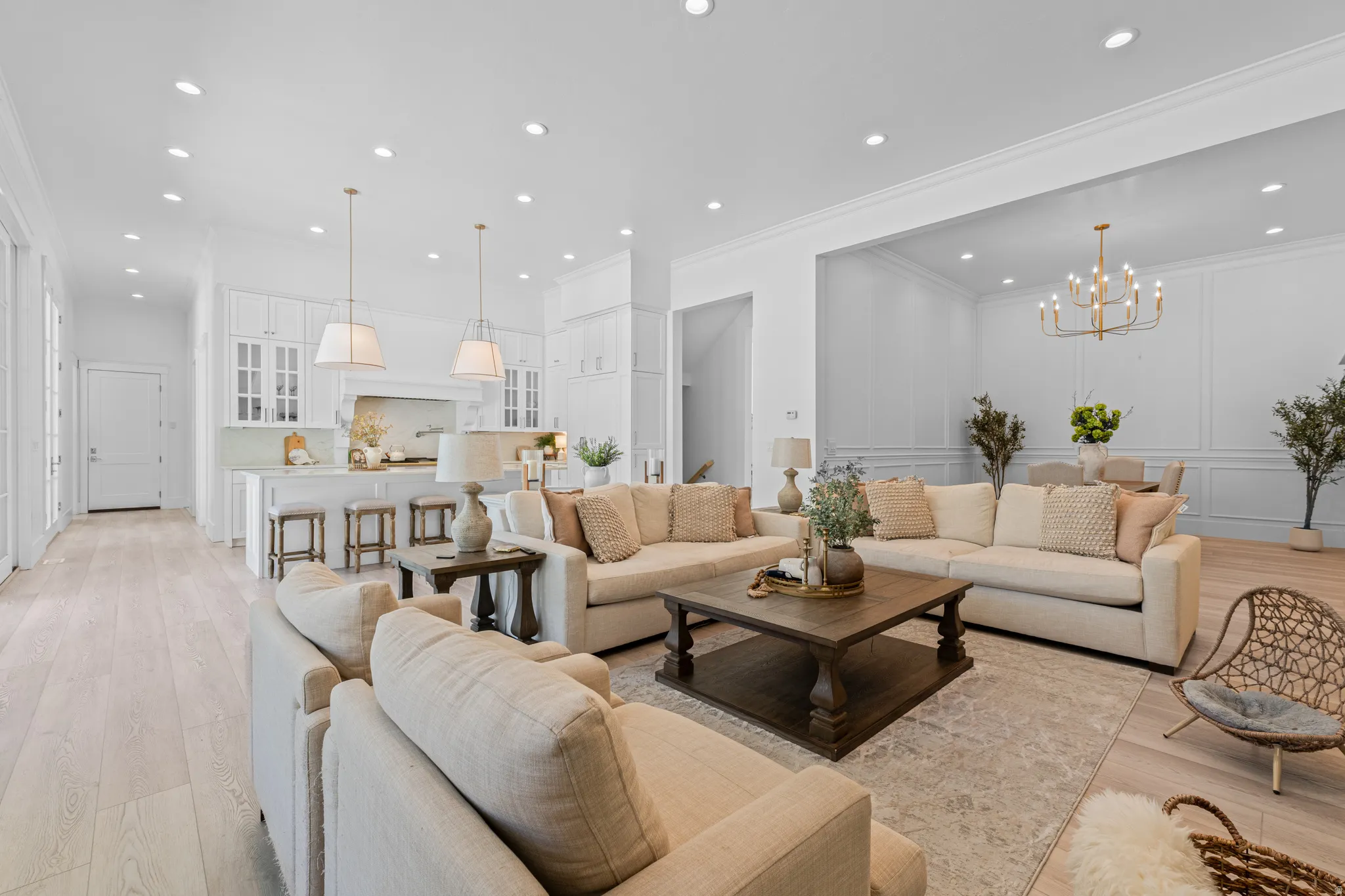 Open-concept living space featuring wood-finish flooring, recessed lighting, and crown molding