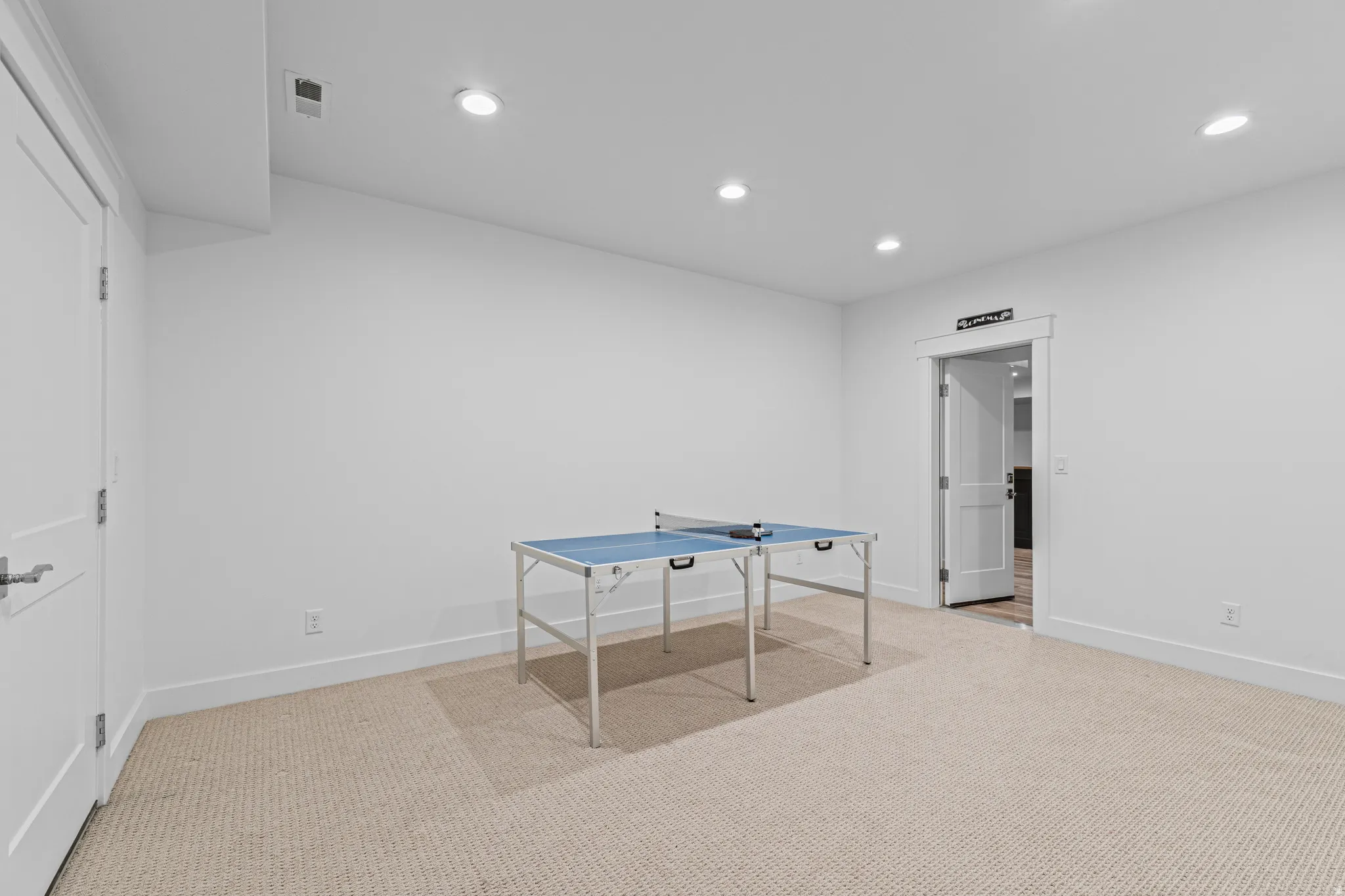 Carpeted recreation room featuring white walls, recessed lighting, and white trim