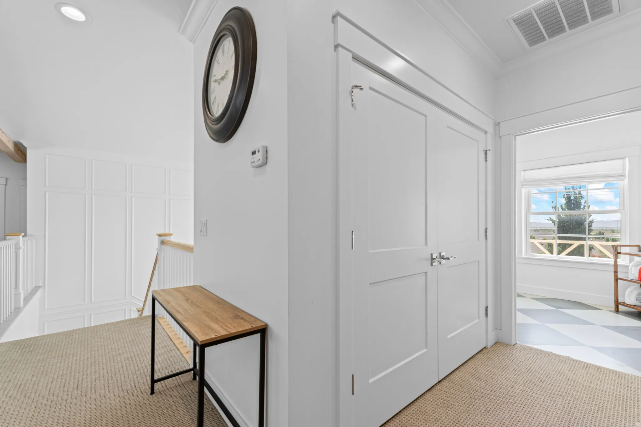 White paneled walls and a light wood handrail define this upper-level landing