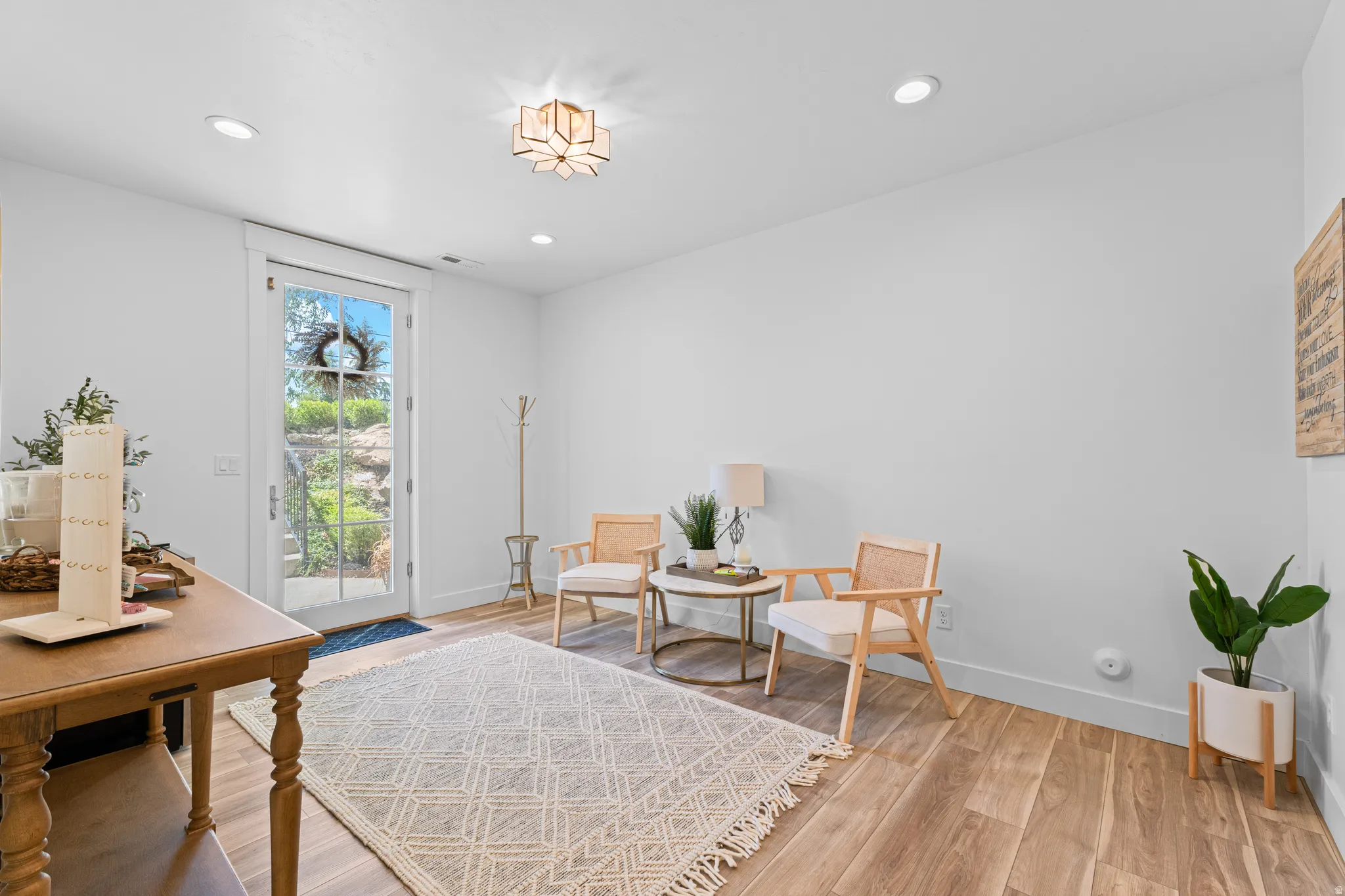 Bright interior room featuring a glass-paneled door, wood-finish flooring, recessed lighting, and a decorative ceiling fixture