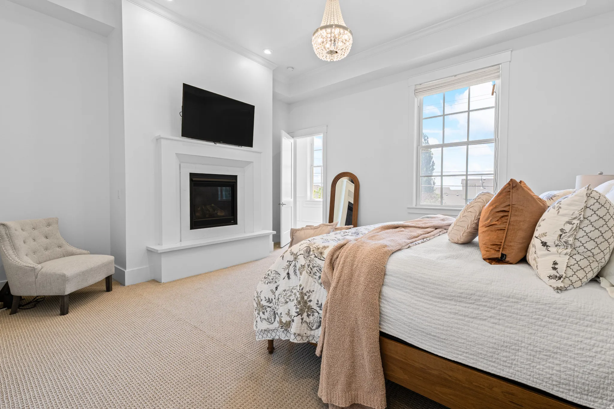 Built-in fireplace with a crisp white mantel, accompanied by recessed lighting and a decorative chandelier
