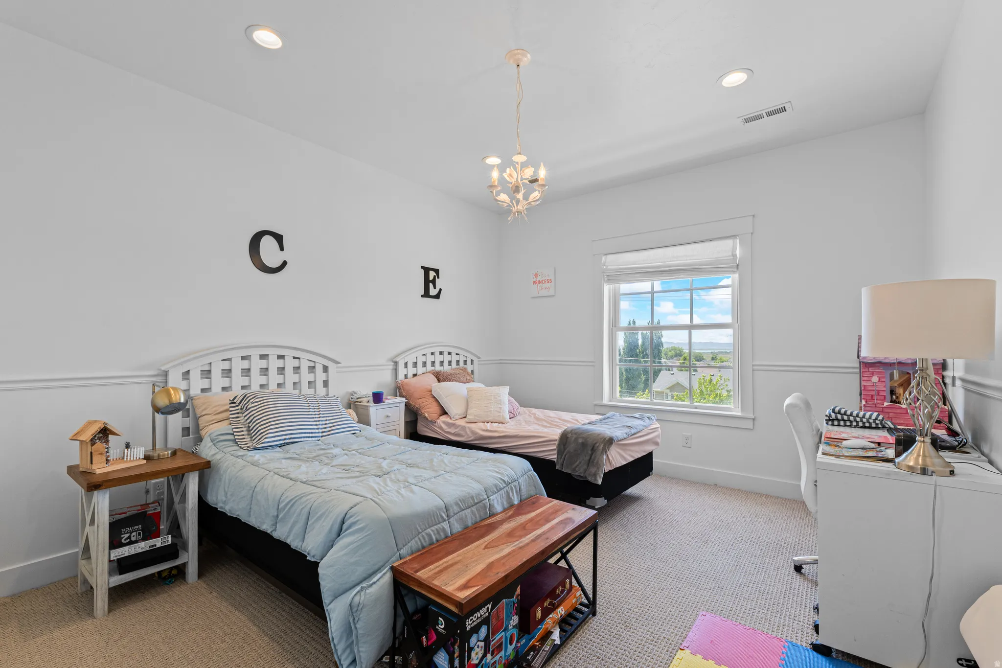 Carpeted interior room featuring a window with a white frame, overhead recessed lighting, a chandelier, and wainscoting