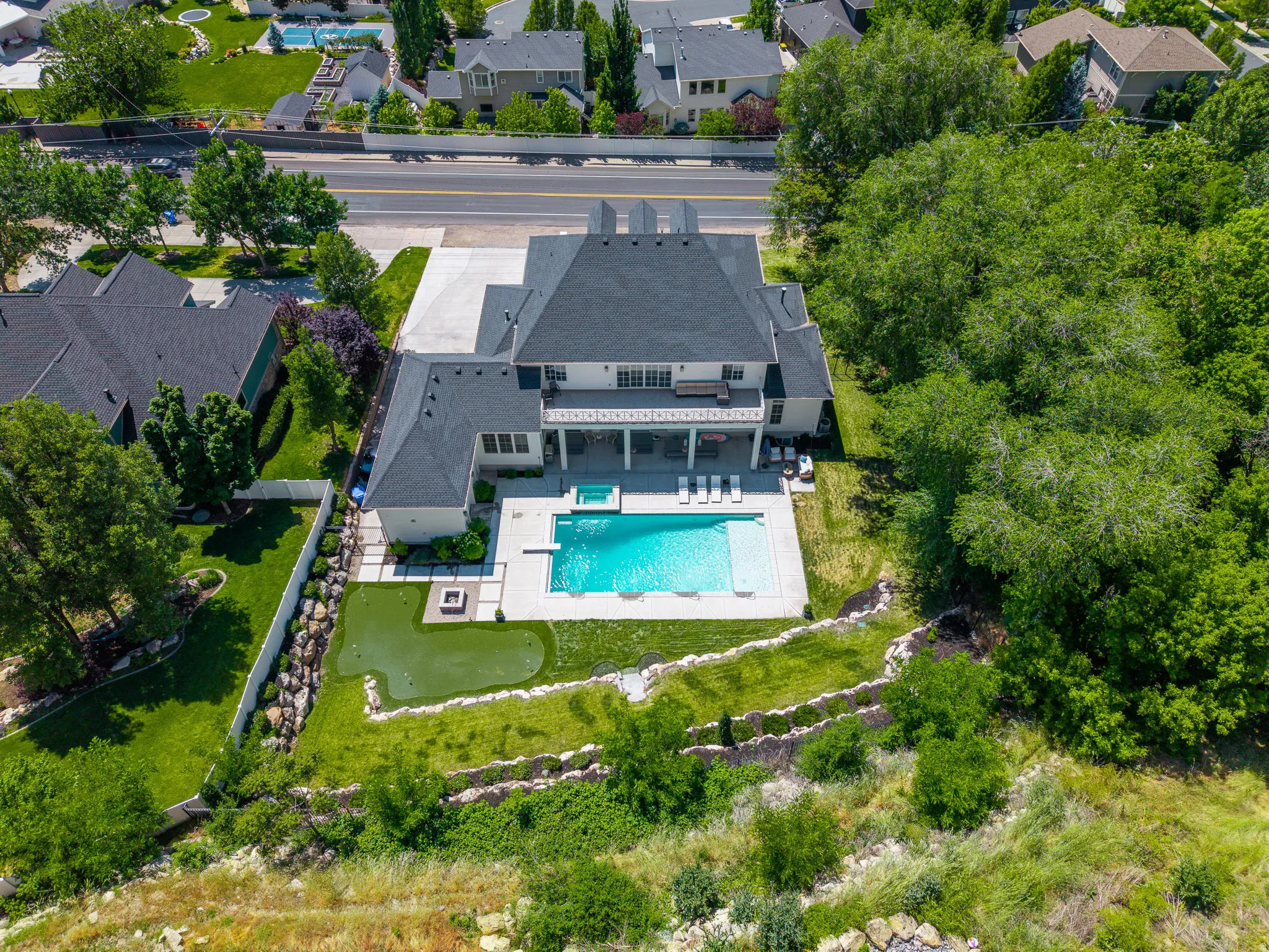 Expansive backyard featuring a rectangular swimming pool, integrated hot tub, and a putting green