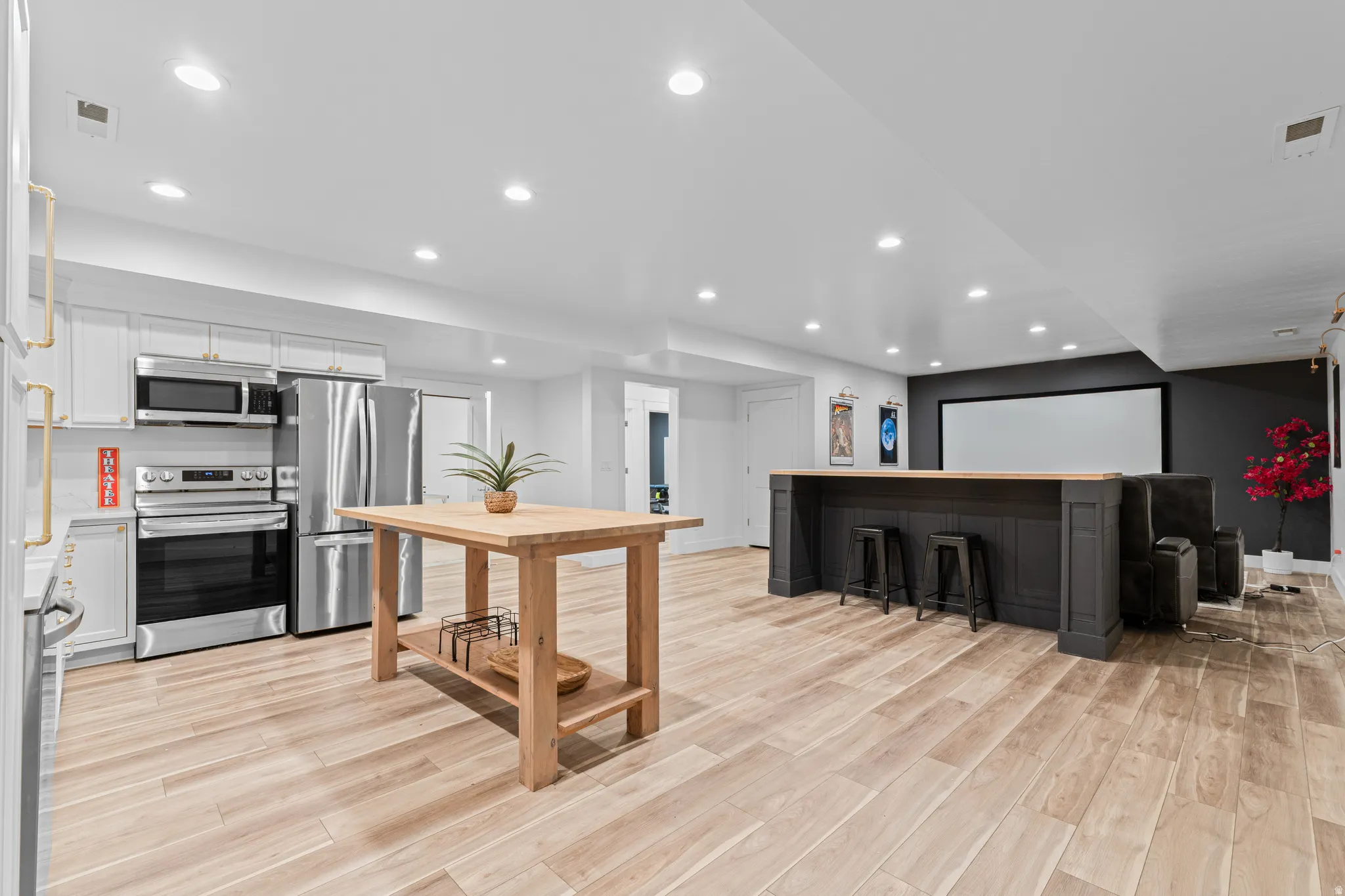 Open-concept entertainment space featuring light wood-finish flooring, recessed lighting, and a white ceiling