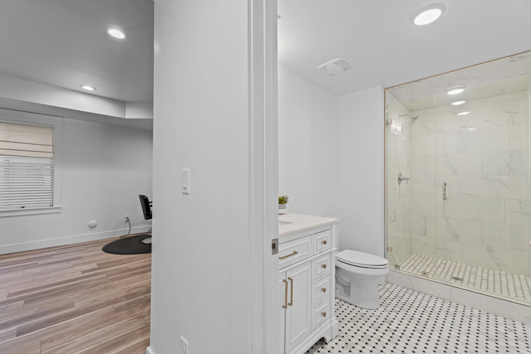 Contemporary bathroom featuring a glass-enclosed shower with large format tile, a vanity with a light-colored countertop, and a black-and-white octagon tile floor