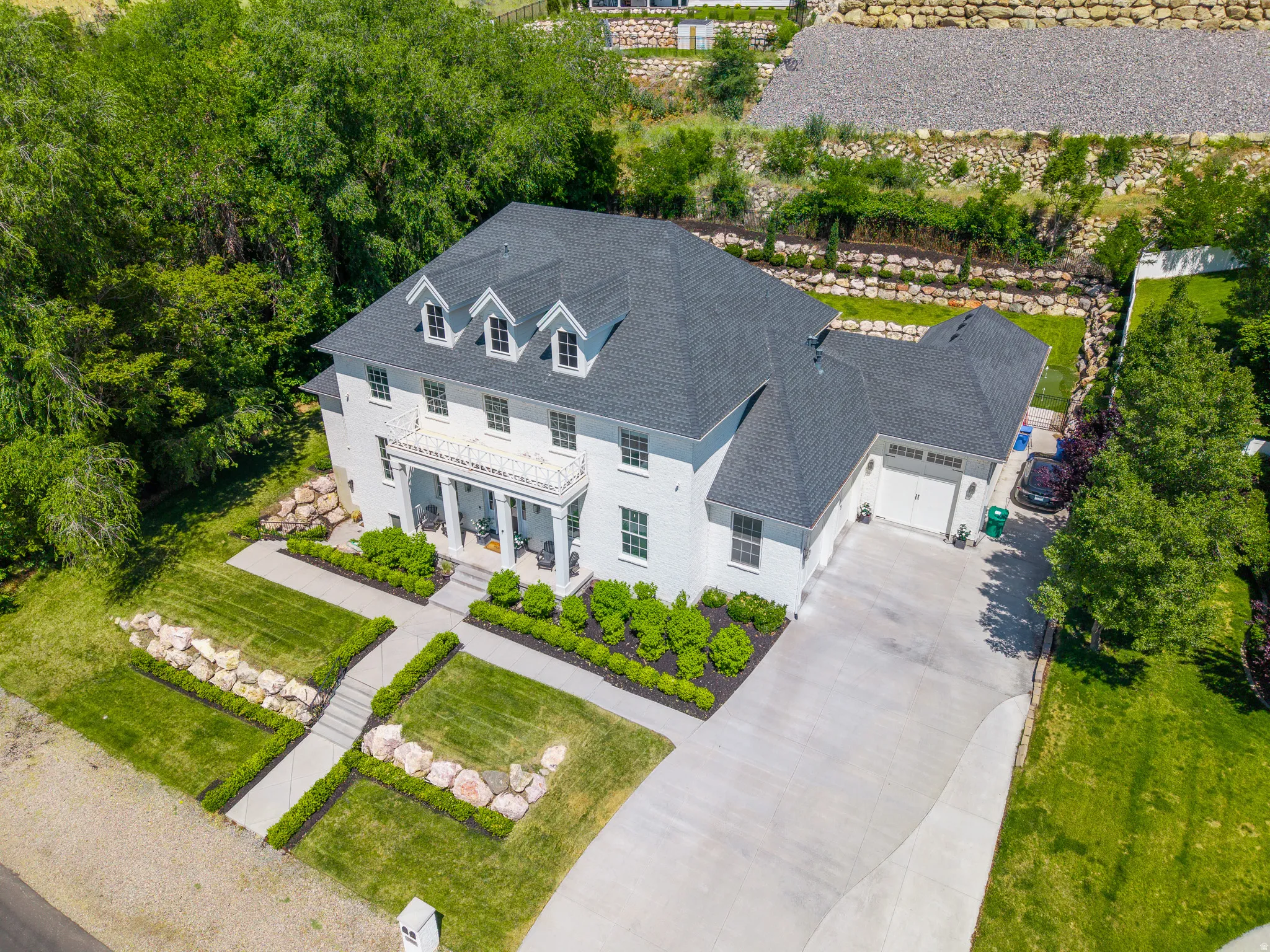Colonial-style residence featuring a prominent portico, dark shingle roof, and a three-car garage