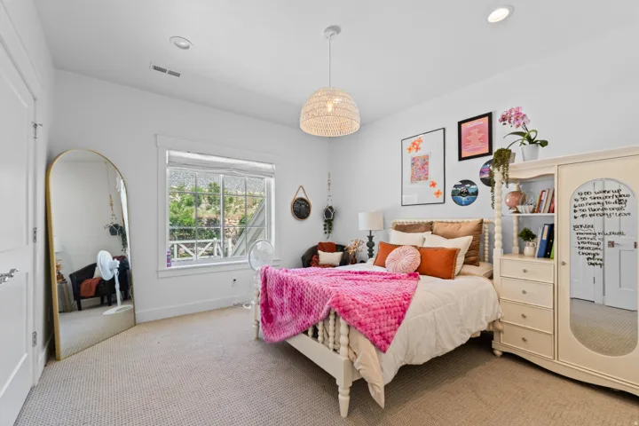 Bright room featuring white walls, textured carpeting, a large window with white trim, and a woven pendant light fixture