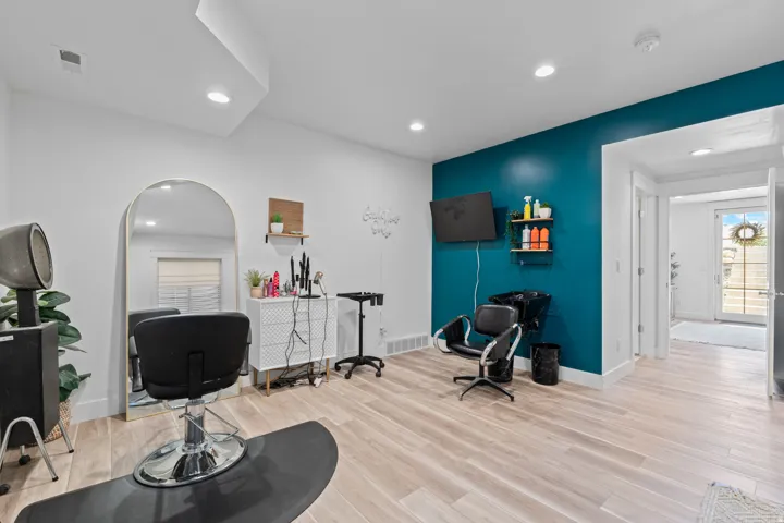 Spacious room featuring wood-finish flooring, a vibrant accent wall, recessed lighting, and a full-light glass door leading to the exterior