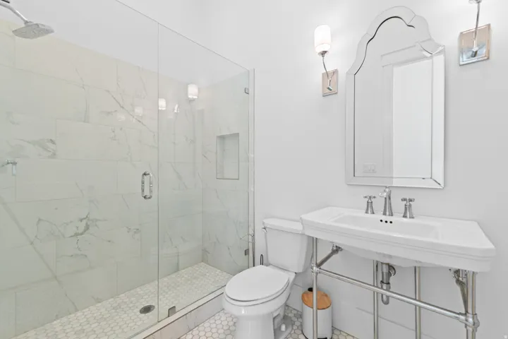 Bathroom featuring a glass-enclosed shower with white marble-look tile, a built-in shower niche, and a rain showerhead