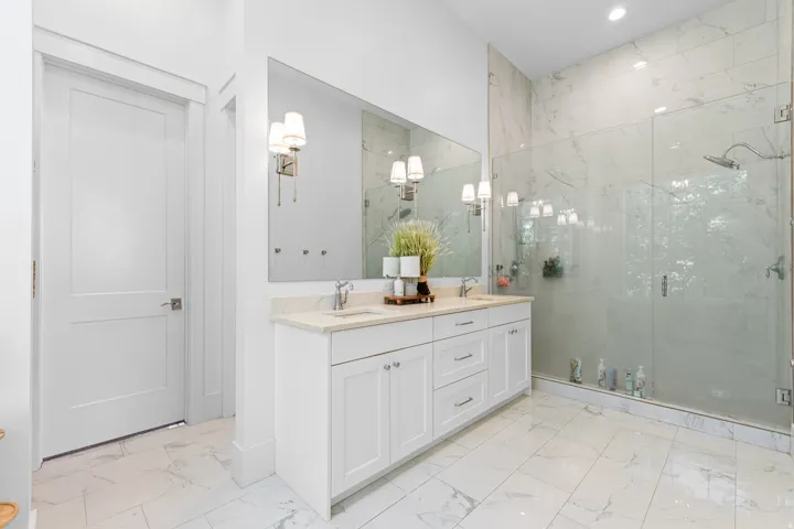 White marble-look tile flooring with a dual vanity featuring light-colored countertops, undermount sinks, and brushed nickel fixtures