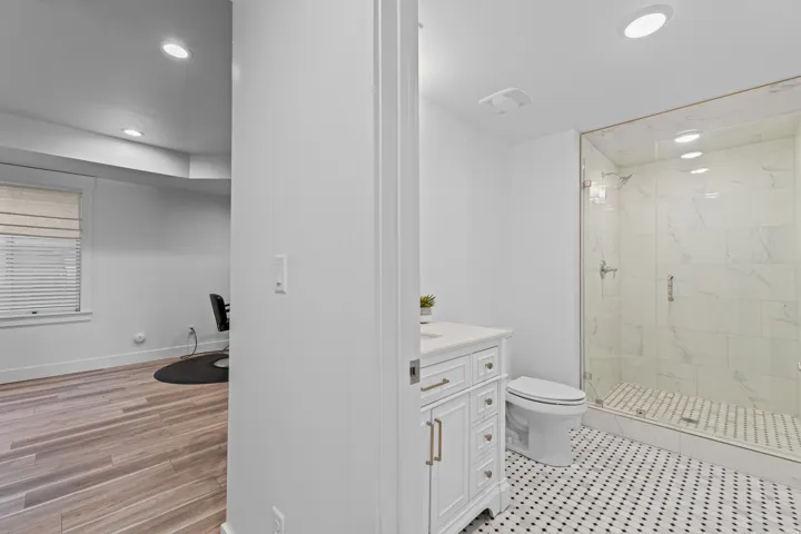 Contemporary bathroom featuring a glass-enclosed shower with large format tile, a vanity with a light-colored countertop, and a black-and-white octagon tile floor
