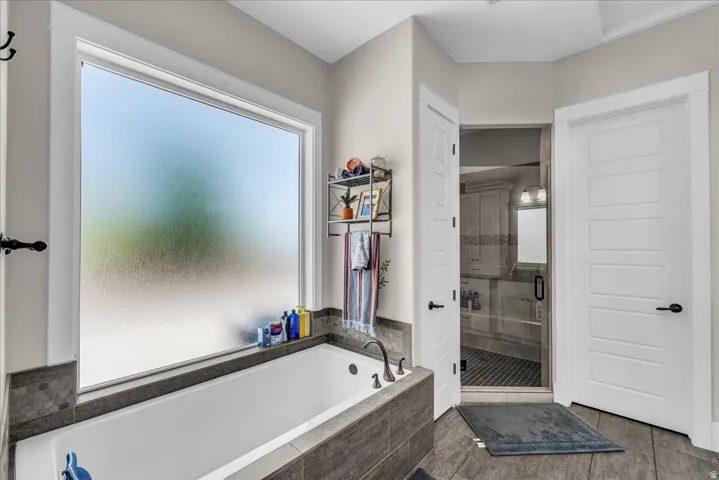 Soaking tub with a large privacy window, surrounded by gray wood-finish tiling