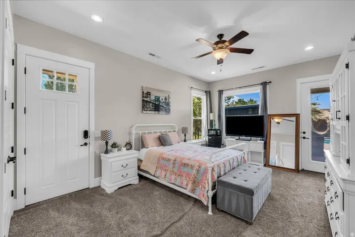 Carpeted room featuring a ceiling fan with integrated lighting, recessed lighting, and a white paneled door with glass inserts