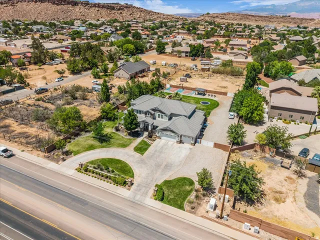 Aerial perspective showcasing the property's expansive lot with a spacious driveway, mature landscaping, and a substantial residential structure featuring a multi-car garage