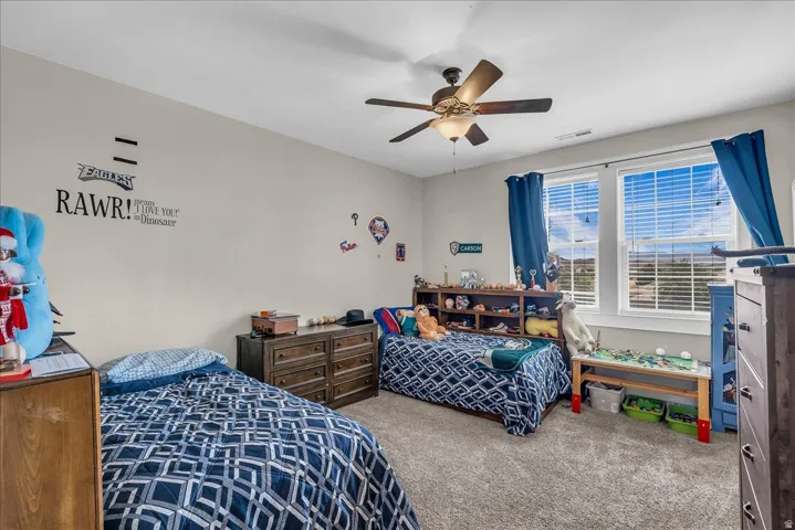Spacious room featuring neutral wall paint, light gray carpet, and a ceiling fan with light fixture