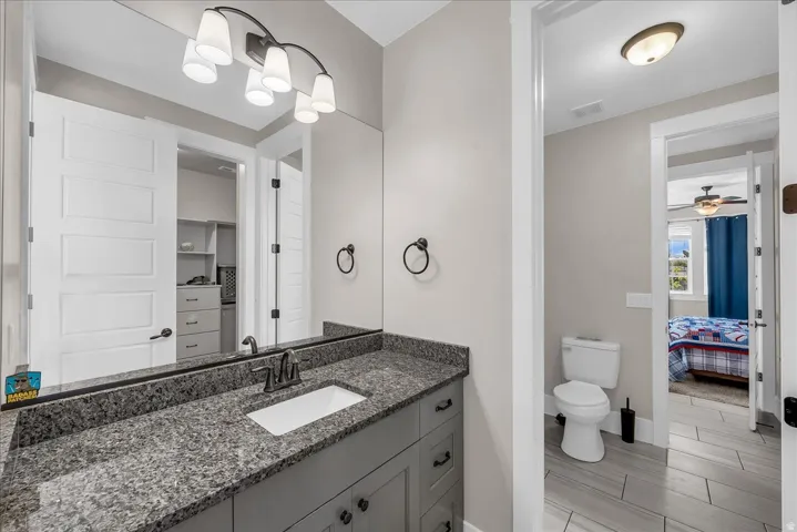 Bathroom vanity with a granite countertop, rectangular undermount sink, and dark bronze faucet