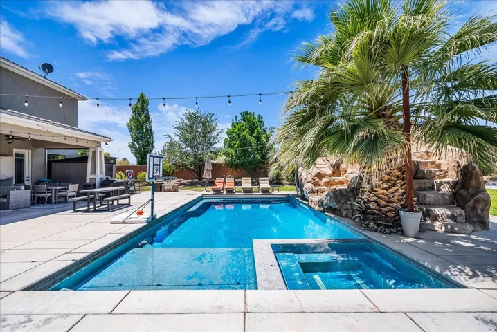 Expansive backyard with a rectangular swimming pool, integrated spa, and surrounding concrete patio