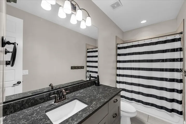 Bathroom featuring a dark speckled countertop, undermount sink, and bronze-finish faucet